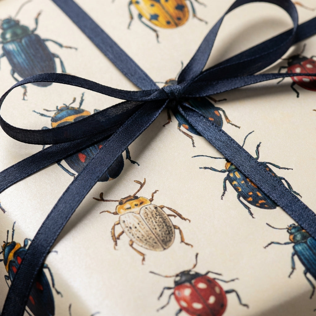 Elegant gift wrapped in beige paper with an insect pattern and tied with a navy blue ribbon.