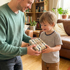 Father gives son a birthday present wrapped in insect print gift wrap with twine ribbon.