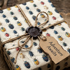 Rustic gift wrapping paper with a colorful beetle pattern, twine bow, and "Adventure Awaits" tag.
