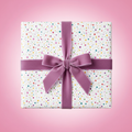 Playful white birthday wrapping paper with colorful confetti dots and a luxurious purple velvet ribbon bow, perfect for any celebration.