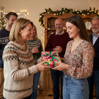 Family exchanging a gift in colorful festive Christmas wrapping paper by Wrapped Studios.