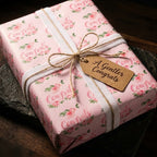 Pink floral congratulations wrapping paper by Wrapped Studios on a gift box with a white ribbon and rustic tag.