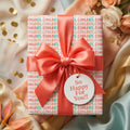 Congratulations wrapping paper with a coral satin bow and celebration gift tag by Wrapped Studios.