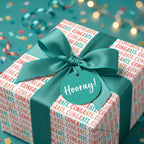 Teal congratulations wrapping paper by Wrapped Studios, featuring a satin bow and festive 'Hooray' gift tag.