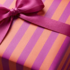 Modern pink and orange striped wrapping paper with a fuchsia satin bow by Wrapped Studios.
