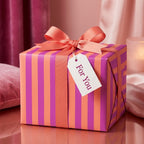 Modern pink and orange striped wrapping paper with a coral ribbon and gift tag by Wrapped Studios.