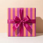 Modern orange and magenta striped wrapping paper with a fuchsia satin bow on a gift box, Wrapped Studios.