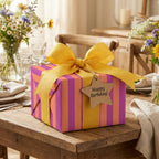 Striped birthday wrapping paper in purple and pink with a yellow ribbon, by Wrapped Studios.