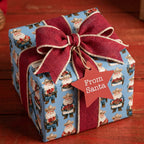 Western Christmas gift wrap with cowboy Santa, red burlap ribbon, and star tag by Wrapped Studios.