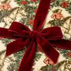Vintage western Christmas wrapping paper with cowgirls on horses, tied with a red velvet bow by Wrapped Studios.