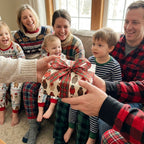Family exchanging a gift in cute bear Christmas wrapping paper with plaid bow by Wrapped Studios.