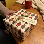 Teddy bear holiday wrapping paper by Wrapped Studios on a gift box tied with a gold bow.