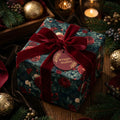 Elegant dark floral Christmas wrapping paper with a red velvet bow and Wrapped Studios gift tag.