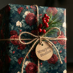 Luxury floral Christmas gift wrap with dark red roses and a Wrapped Studios tag, tied with rustic twine.