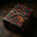 Dark floral wrapping paper gift with twine bow and "Cheers" tag.