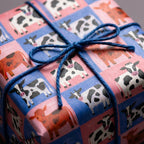 Cute cow print wrapping paper in pink and blue checks, tied with a twine bow by Wrapped Studios.