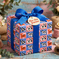 Cute cow print gift wrap with a blue bow and Moo-chas Gracias tag on a gift box by Wrapped Studios.