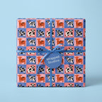 Cute cow print wrapping paper with blue ribbon, playful birthday gift wrap by Wrapped Studios.