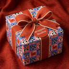 Cute cow print wrapping paper on a gift box with a rustic orange bow by Wrapped Studios.