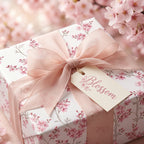 Pink cherry blossom wrapping paper on a gift box with a sheer bow by Wrapped Studios.