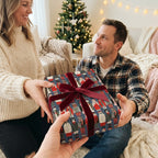 Couple exchanging a present in cute animal Christmas gift wrap with red velvet ribbon by Wrapped Studios.