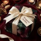 Luxury Christmas wrapping paper with moody green and burgundy pattern and cream bow by Wrapped Studios.