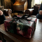 Luxury moody floral wrapping paper with a black satin bow by Wrapped Studios.