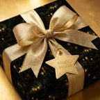 Luxury gift wrapped in black "magic awaits" paper with gold ribbon and star tag.
