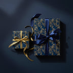 Two gifts wrapped in navy blue floral wrapping paper with gold and navy ribbons.