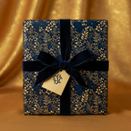 Elegant gift wrapped in navy floral wrapping paper with a velvet navy ribbon and a monogrammed tag.