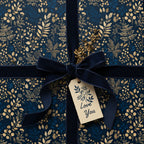 Elegant navy floral wrapping paper with velvet ribbon, gold accents, and "Love You" gift tag.