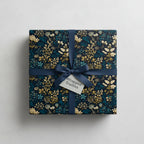 Navy and gold floral wrapping paper with satin ribbon, perfect for birthday or Christmas gifts.