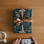 Elegant floral wrapping paper in navy and gold, tied with a copper ribbon.