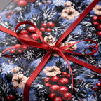 Luxury Christmas wrapping paper in blue winter floral and red berry pattern with a red ribbon by Wrapped Studios.