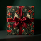 Luxury Christmas wrapping paper with red berry and pine pattern, tied with a burgundy satin bow by Wrapped Studios.