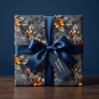 Luxury Christmas wrapping paper with winter botanical design and navy blue ribbon by Wrapped Studios.