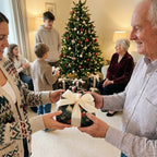 Family sharing gifts wrapped in green botanical Christmas wrapping paper by Wrapped Studios.