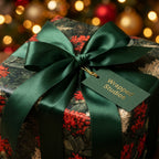 Luxury botanical Christmas wrapping paper with dark green ribbon and gift tag by Wrapped Studios.