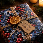 Christmas gift wrap with winter botanical print by Wrapped Studios, tied with twine and a dried orange.
