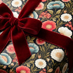 Dark vintage floral wrapping paper with a red velvet bow, elegant luxury gift wrap by Wrapped Studios.