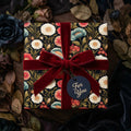 Luxury dark floral wrapping paper by Wrapped Studios, tied with a deep red velvet bow.