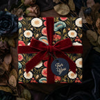 Luxury dark floral wrapping paper by Wrapped Studios, tied with a deep red velvet bow.