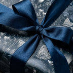 Moody botanical wrapping paper with mushrooms and butterflies, tied with navy satin ribbon by Wrapped Studios.