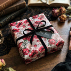 Vintage botanical wrapping paper with red flowers and mushrooms by Wrapped Studios, tied with a black ribbon.