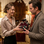 Couple exchanging a gift in luxury Christmas wrapping paper with a red velvet bow by Wrapped Studios.