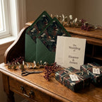 Forest green botanical wedding wrapping paper and matching invitations on a rustic desk by Wrapped Studios.