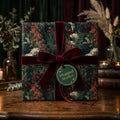 Luxury dark floral wrapping paper with a burgundy velvet bow on a gift box, by Wrapped Studios.