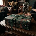 Moody floral wrapping paper with a green velvet ribbon on a luxury gift box by Wrapped Studios.
