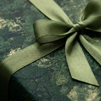 Luxury forest green botanical wrapping paper with a satin ribbon bow by Wrapped Studios.