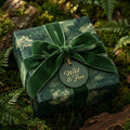 Botanical forest wrapping paper with a green velvet bow. Luxury woodland gift wrap by Wrapped Studios.